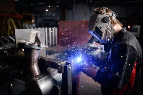 Young man soldering large metal pipe.