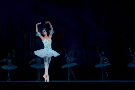 Ballerina in blue costume performing on stage.