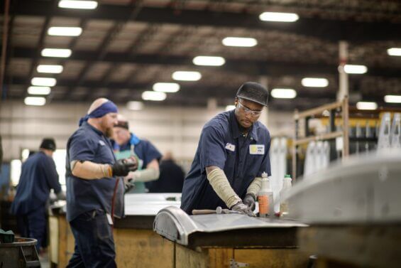 Man smoothing piece of metal with hands.