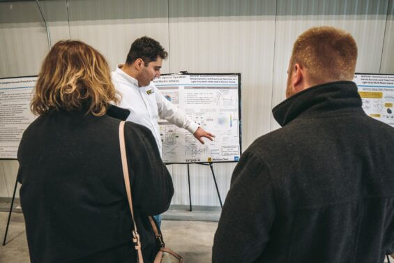 Electric Vehicle researcher explaining work to passerybyers.