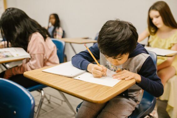 Boy working at a wooden desk in class.