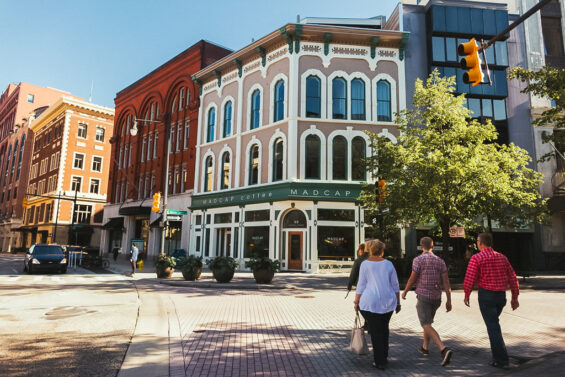 people walk across a street to a coffee shop