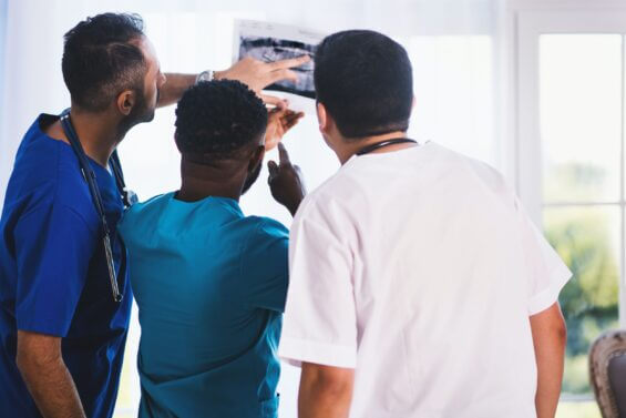 Three doctors analyze a x-ray in the sun.