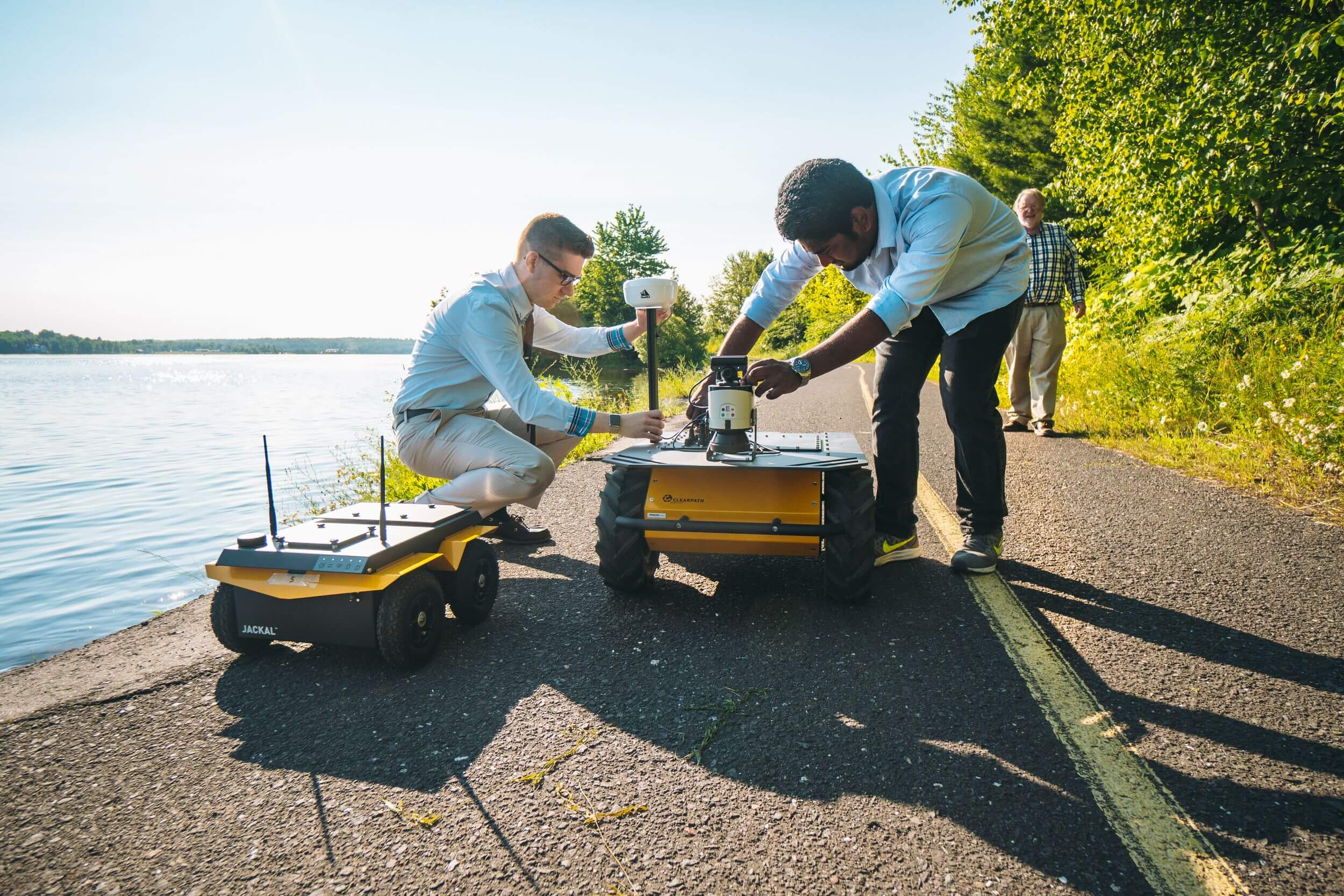 Two students prep robots for outdoor run.