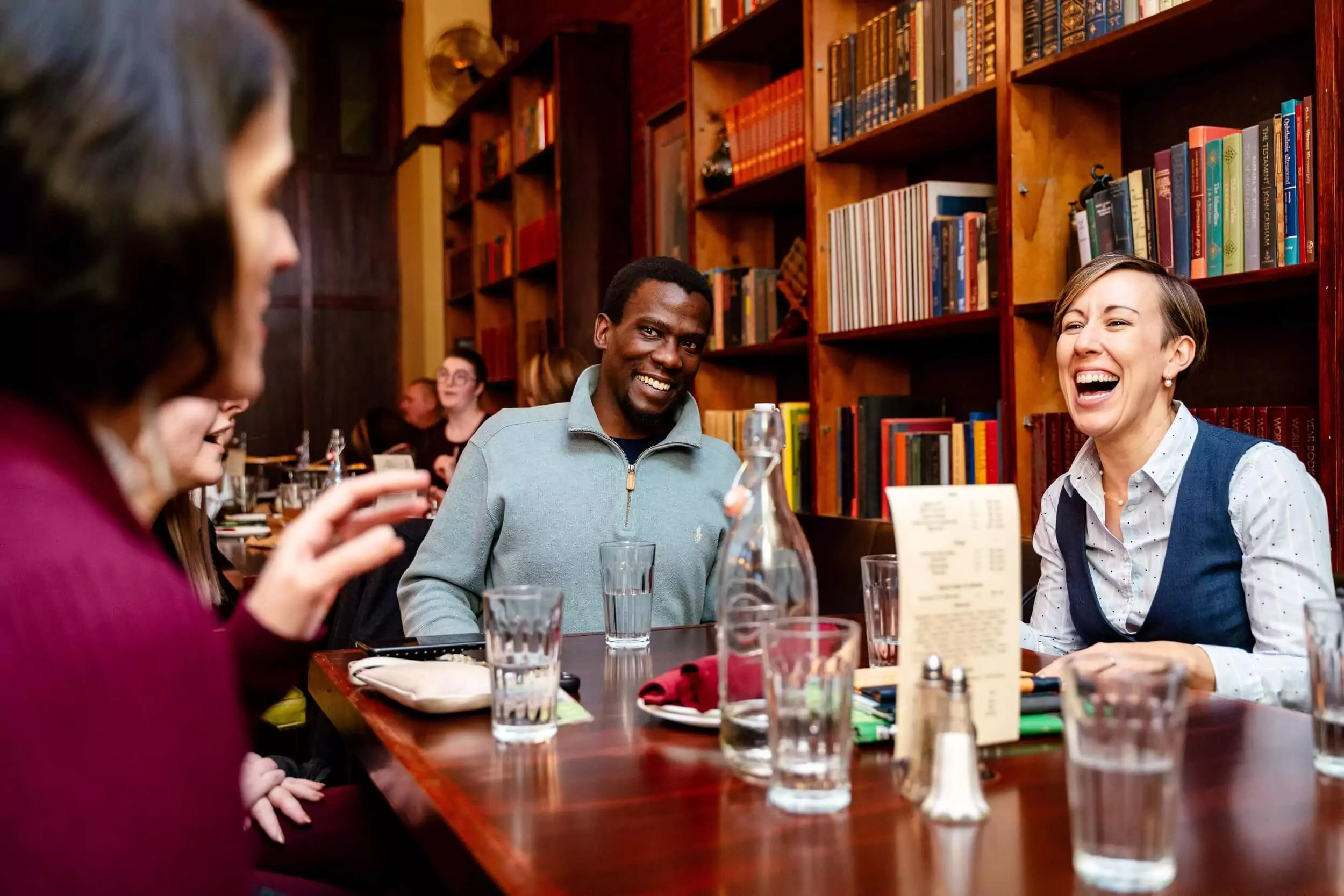 Group of friends laugh at restaurant.