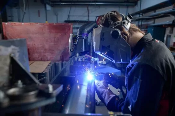 Young man solders a metal pipe.