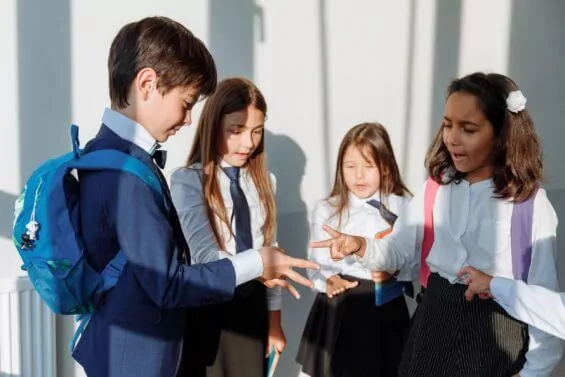 Students in uniforms play "rock, paper, scissors."