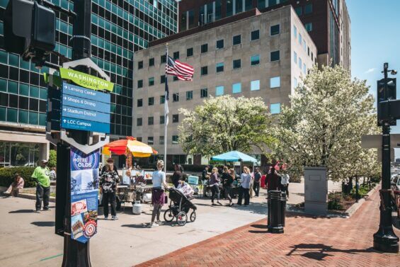 People walk on a busy sidewalk alongside street vendors in downtown Lansing, the capital of Michigan.
