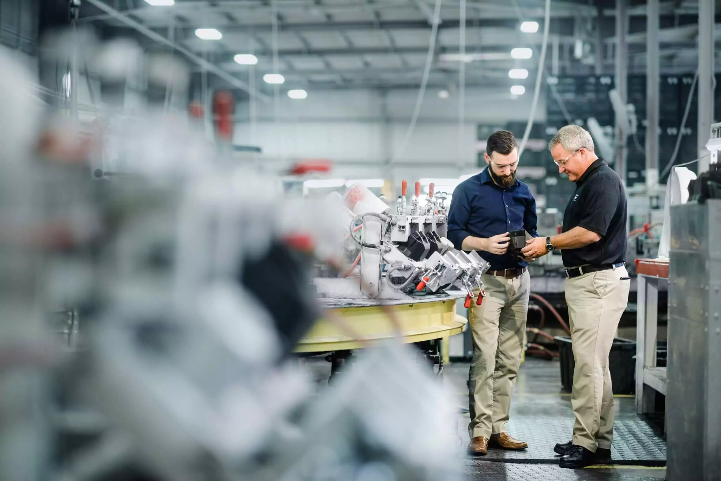 Two men examine their product in a factory.