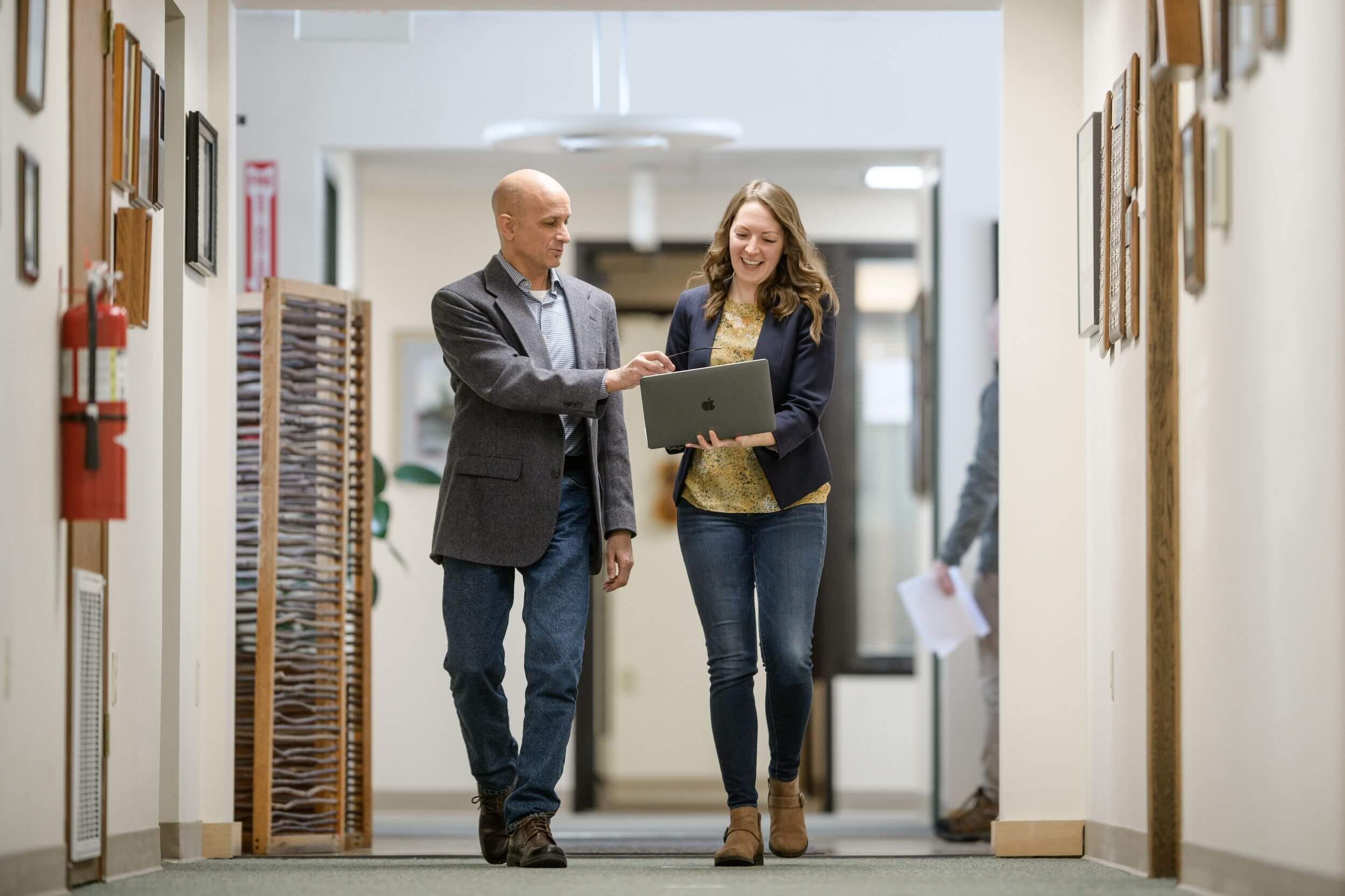 Woman and man walk down office hallway.