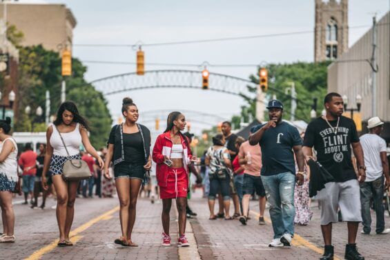 Group of friends walks down a closed street during downtown Flint's Alley Fest.
